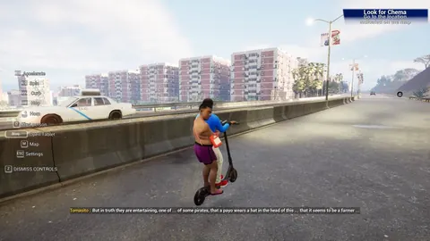 Wan en patinete por una avenida de Boquerón City con bloques de viviendas al fondo